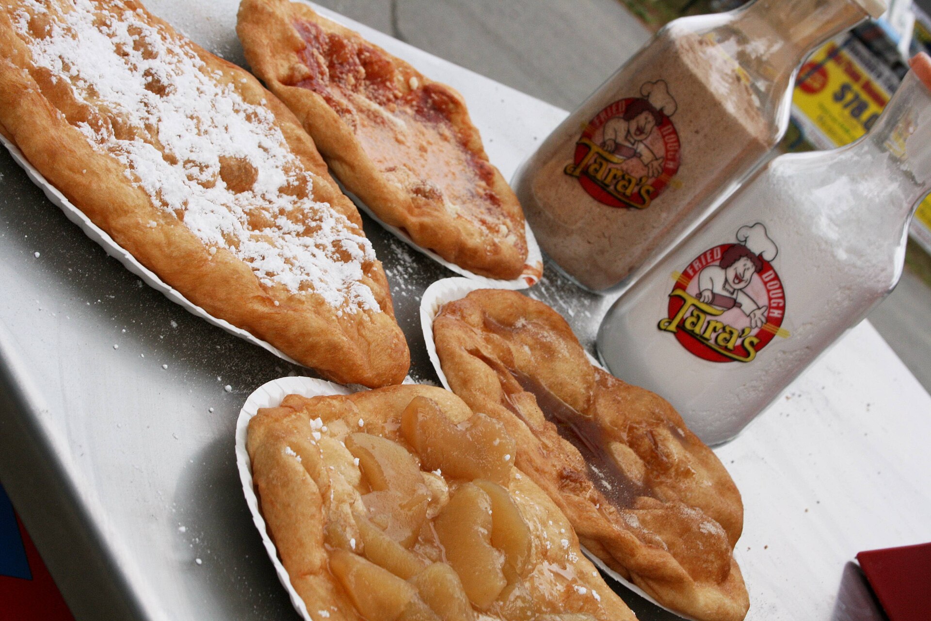 Rombi di pasta fritta gonfi e dorati appena scolati, ammucchiati su un piatto con carta assorbente