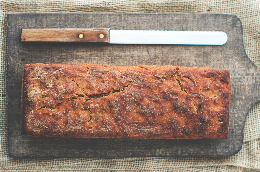 Pagnotta rustica con crosta spessa tagliata a metà sopra un tagliere di legno
