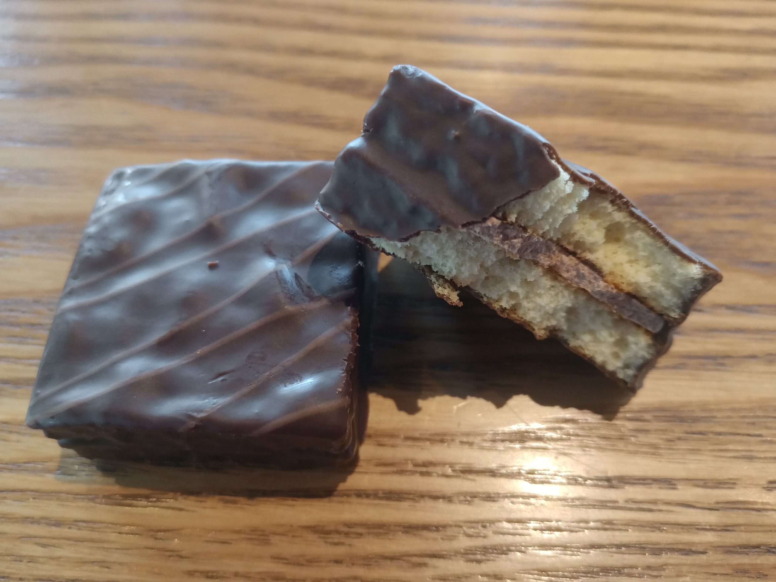 Fetta di torta scura di nocciole con briciola densa appoggiata su un piatto bianco