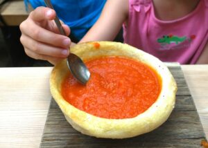Scodella di zuppa densa di pomodoro con un filo d'olio e una foglia di basilico