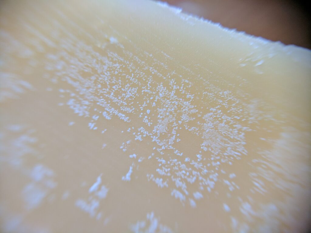 Primo piano di una fetta di formaggio stagionato con piccoli cristalli bianchi visibili
