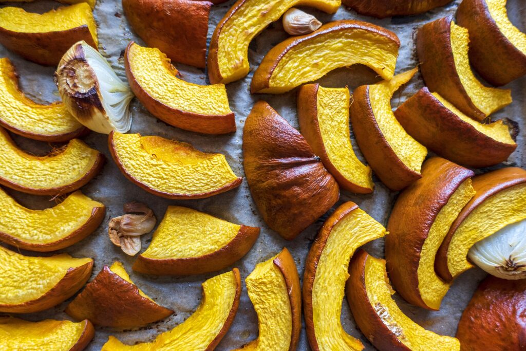 Fette di zucca cotte in forno con i bordi scuriti su una teglia da forno