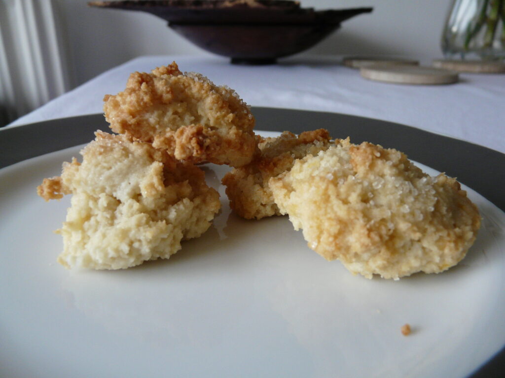 Piccoli biscotti secchi alla mandorla su un piattino, alcuni interi e alcuni sbriciolati
