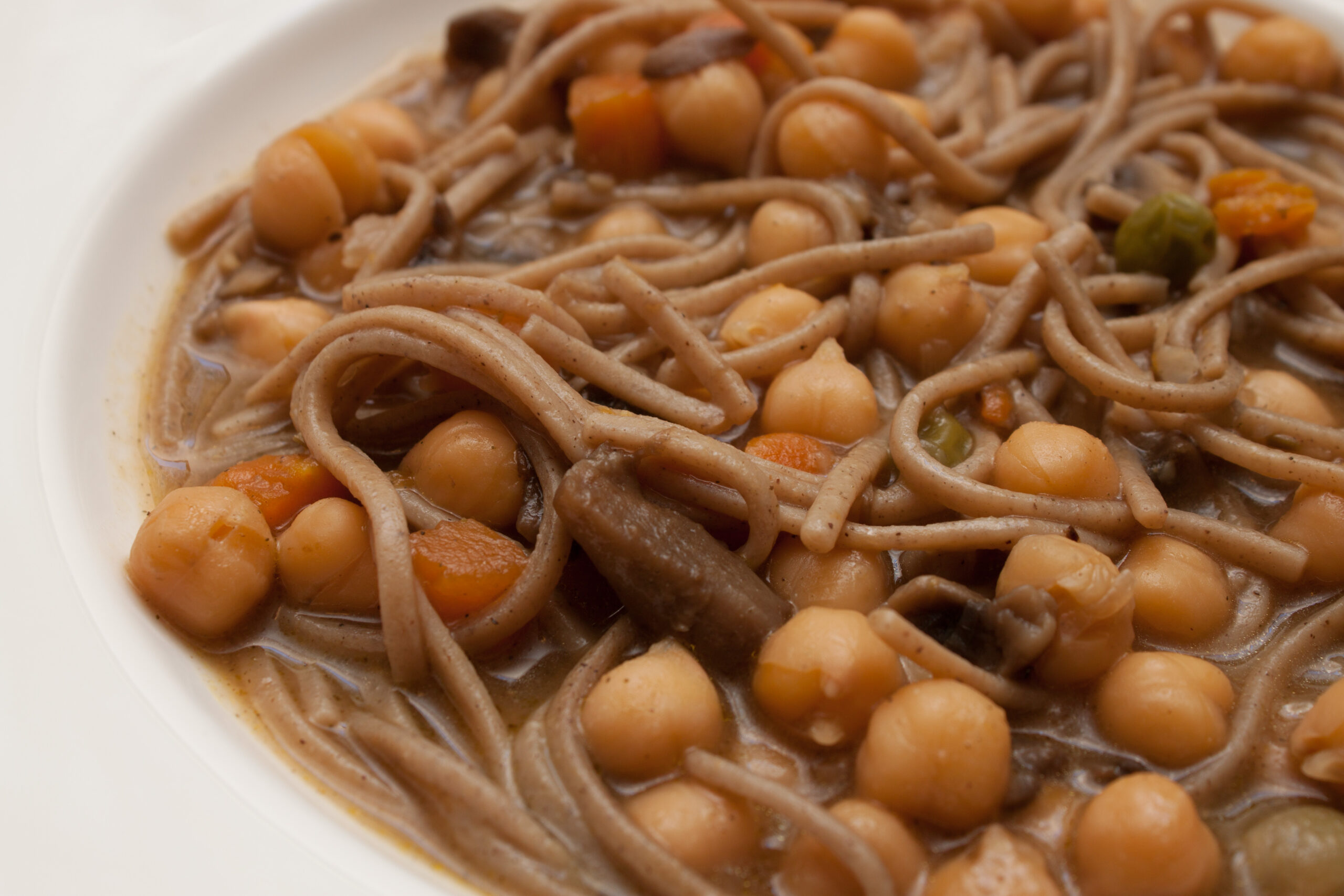 Scodella di zuppa densa di legumi con un filo d'olio e rosmarino appoggiato sul bordo