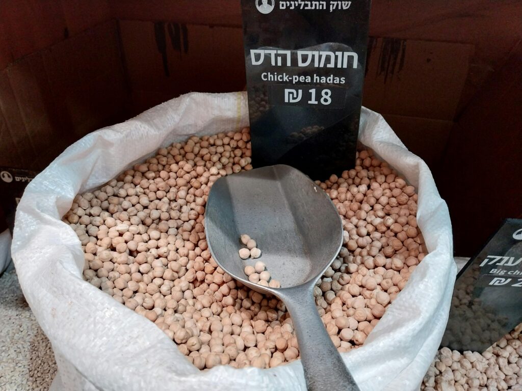 Ceci secchi color avorio raccolti in una ciotola di terracotta accanto a un cucchiaio