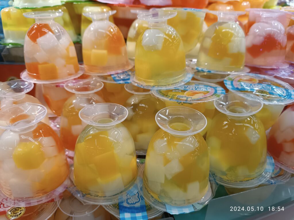 Vasetti di vetro pieni di gelatina ambrata allineati su un ripiano illuminato